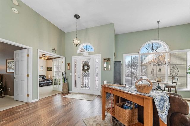 foyer entrance with a high ceiling, wood-type flooring, and a chandelier