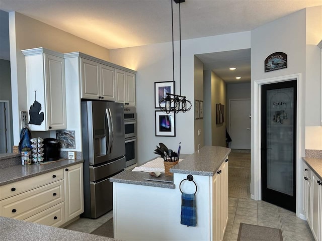 kitchen featuring light tile patterned floors, white cabinetry, stainless steel appliances, a kitchen island, and decorative light fixtures
