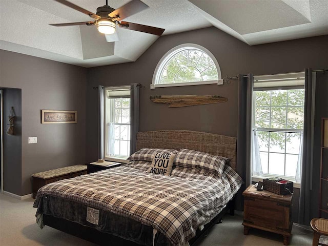 carpeted bedroom with multiple windows, ceiling fan, vaulted ceiling, and a textured ceiling