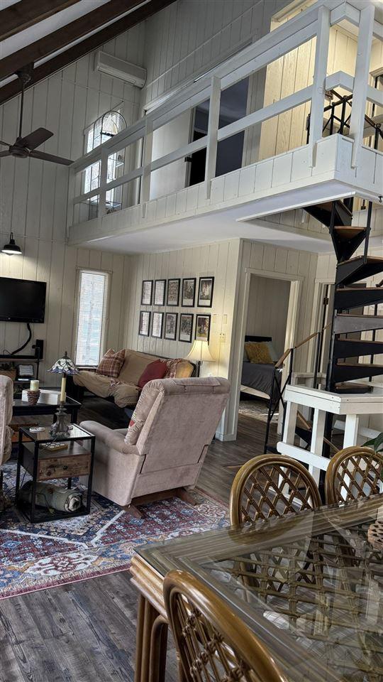 living area with wood walls, wood finished floors, and a towering ceiling