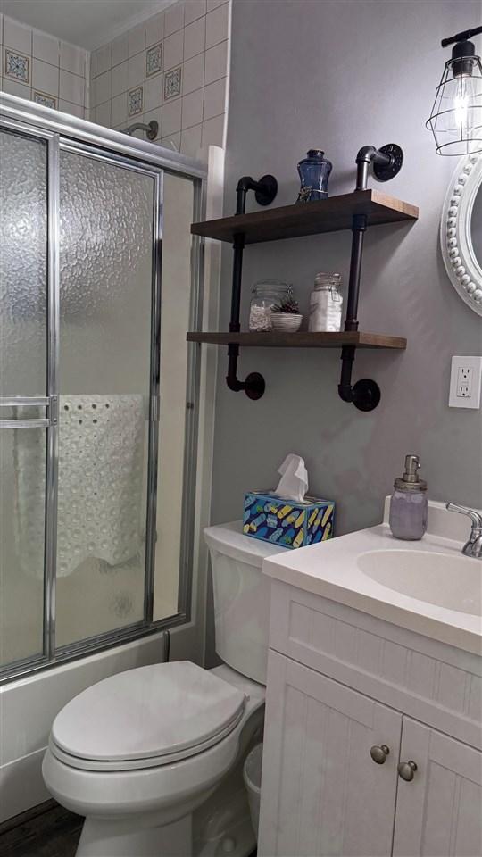 bathroom featuring vanity, toilet, and enclosed tub / shower combo