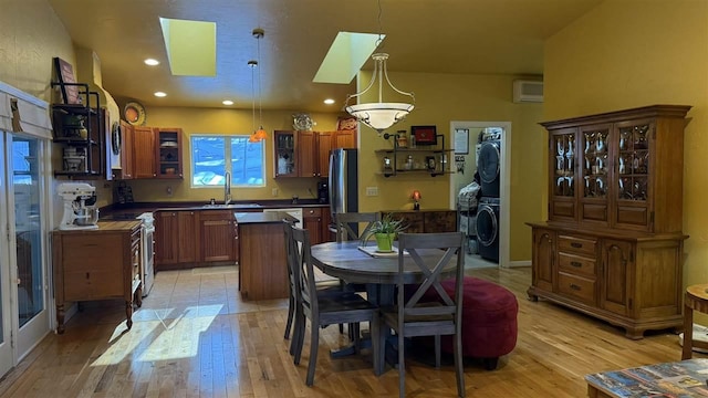kitchen with a skylight, a wall mounted AC, light wood-type flooring, stacked washer / drying machine, and freestanding refrigerator