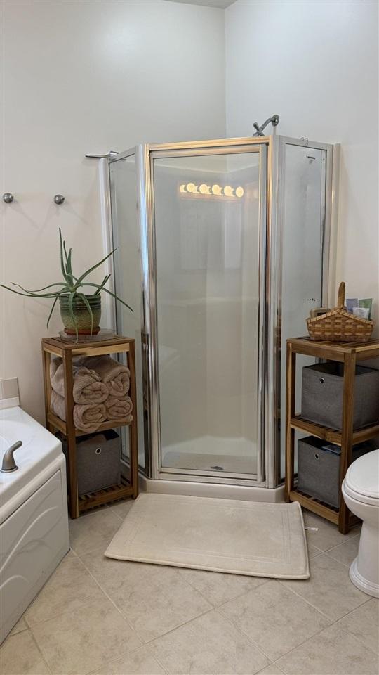 full bath featuring toilet, a garden tub, tile patterned flooring, and a stall shower