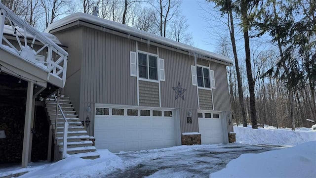 view of snowy exterior with a garage and stairway