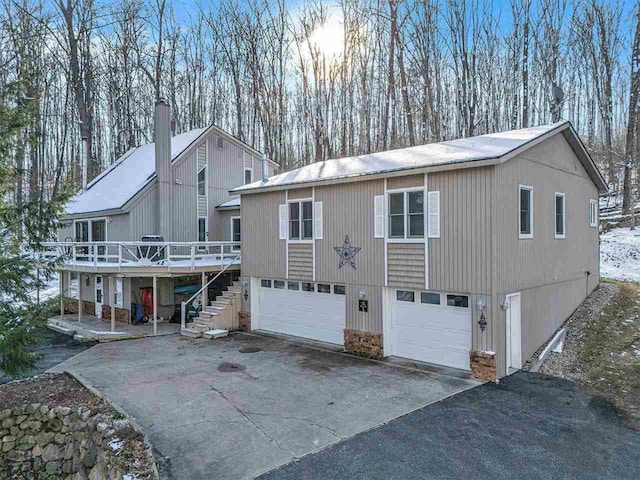 rear view of property with a wooden deck, aphalt driveway, stairs, and a garage