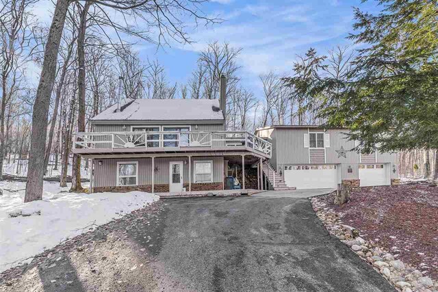 view of front of home featuring driveway, a deck, stairs, and a garage