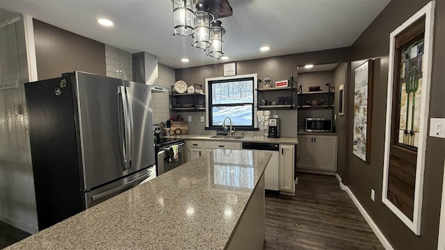kitchen with wall chimney exhaust hood, a sink, open shelves, light stone countertops, and appliances with stainless steel finishes
