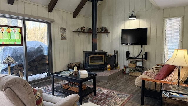 living area with lofted ceiling with beams, wood finished floors, wood walls, and a wood stove