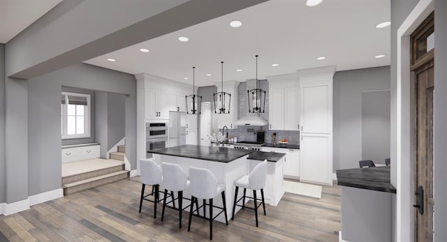 kitchen with a kitchen bar, decorative light fixtures, a center island, appliances with stainless steel finishes, and white cabinets