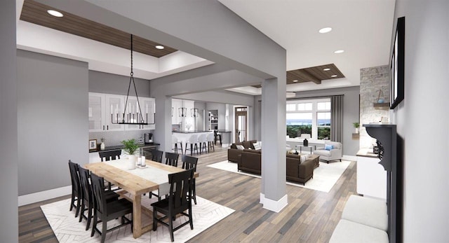 dining space with a raised ceiling, hardwood / wood-style floors, and an inviting chandelier