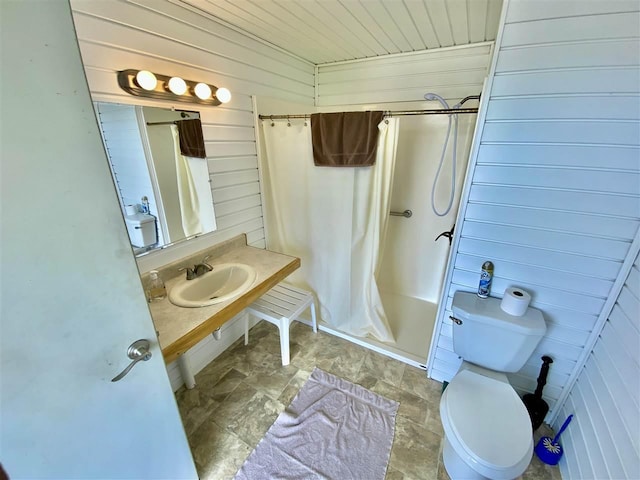 bathroom featuring toilet, sink, and wood walls