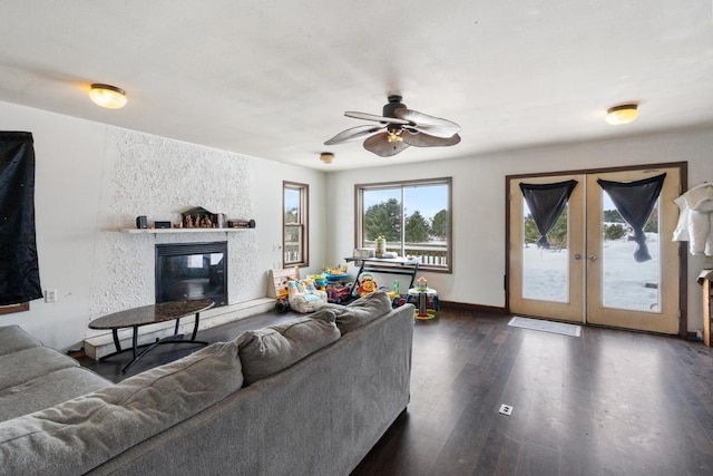 living room featuring a large fireplace, dark wood-type flooring, ceiling fan, and french doors