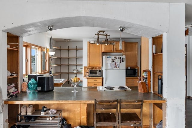 kitchen with decorative light fixtures, a breakfast bar area, kitchen peninsula, and white fridge