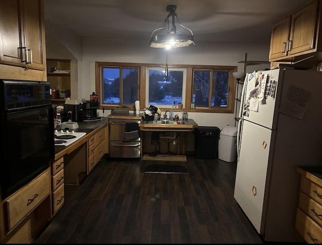 kitchen featuring dark hardwood / wood-style floors, black oven, sink, hanging light fixtures, and white fridge