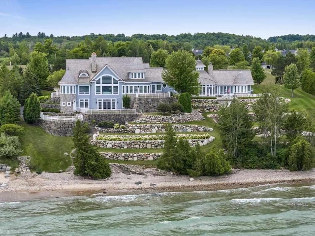 rear view of house with a water view and a view of the beach