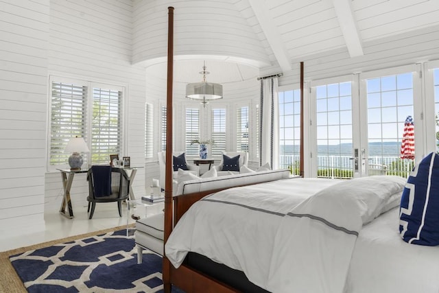 bedroom with a water view, beamed ceiling, multiple windows, and access to outside