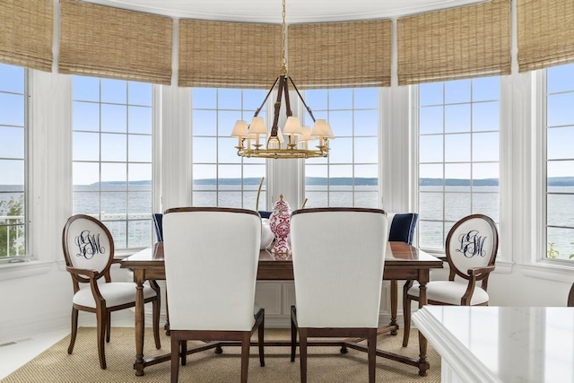 dining room with a water view and a notable chandelier