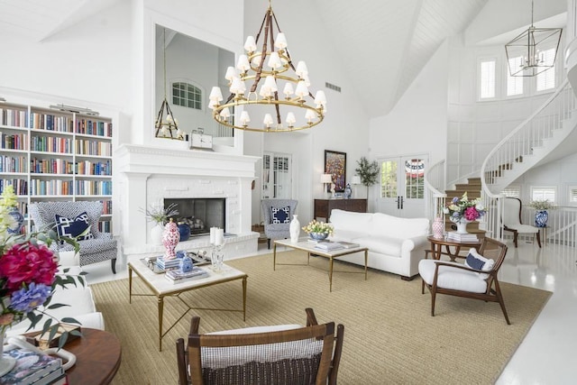 living room with a towering ceiling, a chandelier, and french doors