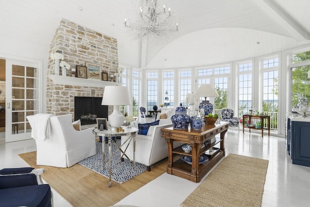 living room featuring vaulted ceiling, a stone fireplace, and an inviting chandelier