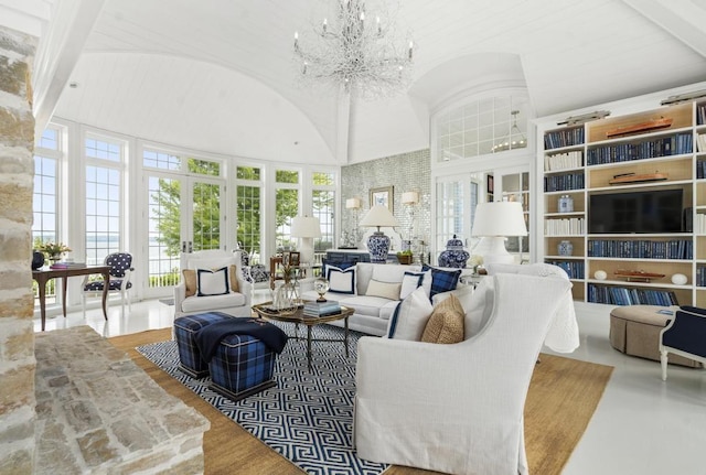 living room with vaulted ceiling, an inviting chandelier, and french doors