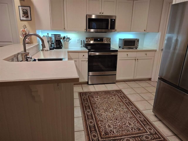 kitchen with tasteful backsplash, light tile patterned floors, stainless steel appliances, and sink