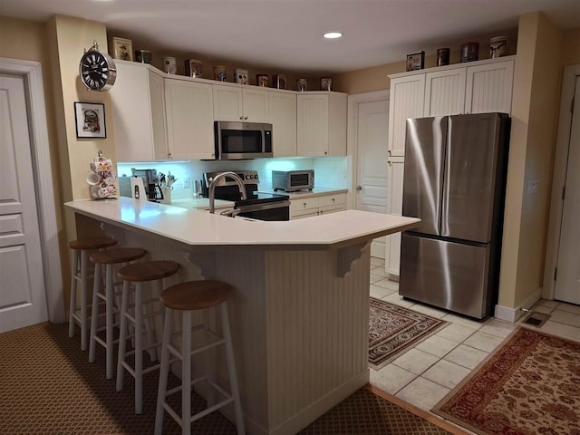 kitchen featuring stainless steel appliances, kitchen peninsula, and a breakfast bar area