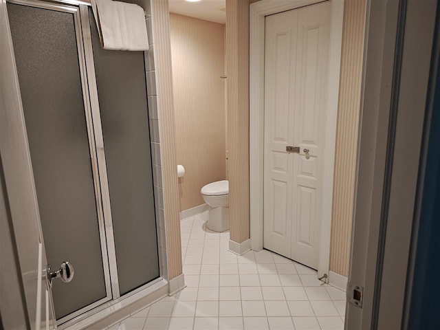 bathroom featuring toilet, a shower with shower door, and tile patterned flooring