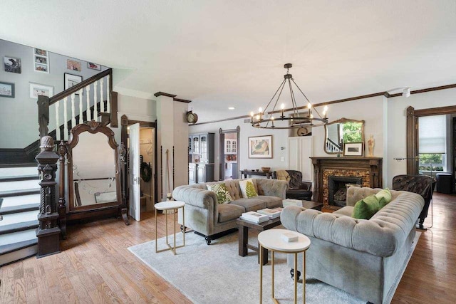 living room featuring an inviting chandelier, hardwood / wood-style flooring, a fireplace, and ornamental molding