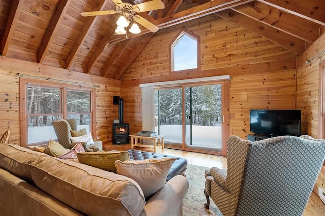 living room featuring wood walls, wood-type flooring, wooden ceiling, a wood stove, and beamed ceiling