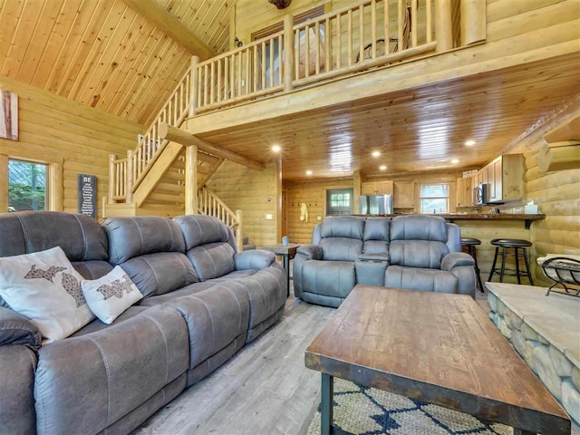 living room with high vaulted ceiling, wooden ceiling, wooden walls, log walls, and light hardwood / wood-style floors