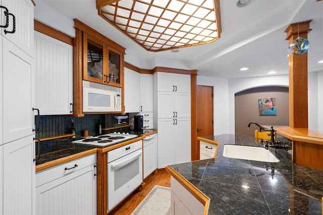 kitchen featuring hardwood / wood-style floors, sink, backsplash, white cabinets, and white appliances