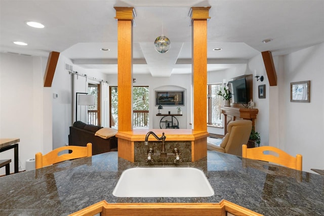 kitchen with a barn door, kitchen peninsula, sink, and ornate columns