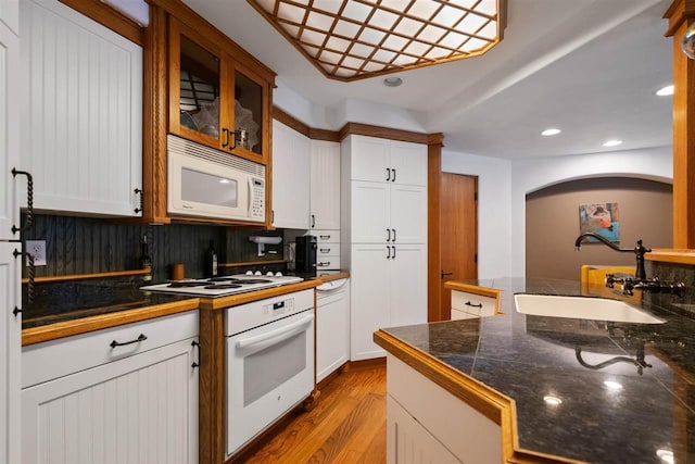 kitchen with sink, white cabinets, white appliances, and light hardwood / wood-style flooring