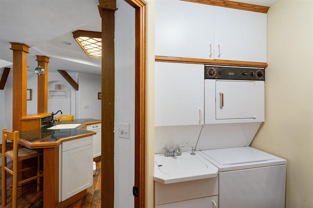 laundry area featuring ornate columns, cabinets, sink, and stacked washer and dryer