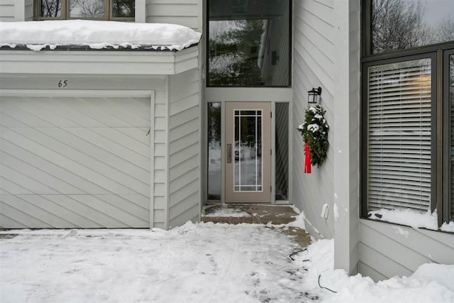 snow covered property entrance featuring a garage