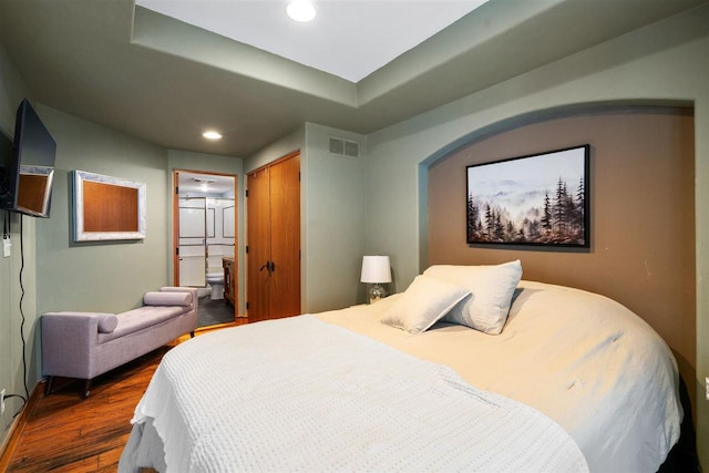 bedroom featuring dark hardwood / wood-style flooring, connected bathroom, and a closet