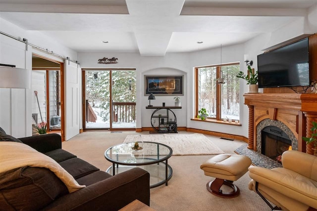 living room with light colored carpet, a barn door, and a healthy amount of sunlight