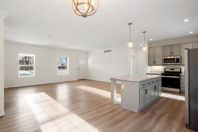 kitchen with pendant lighting, a kitchen island, gray cabinets, and appliances with stainless steel finishes