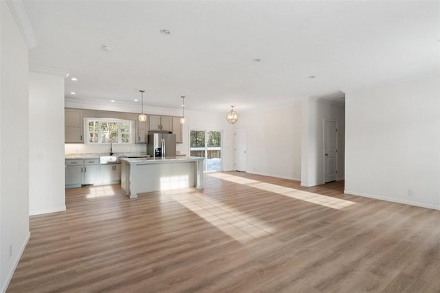 unfurnished living room featuring crown molding, an inviting chandelier, and light hardwood / wood-style flooring