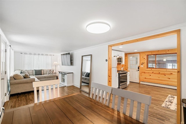 dining space with crown molding, wood-type flooring, and a baseboard heating unit