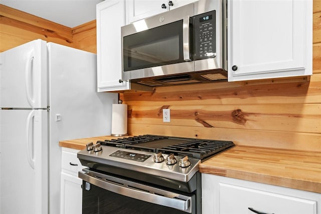 kitchen with butcher block countertops, white cabinets, and appliances with stainless steel finishes