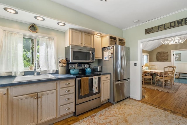 kitchen with lofted ceiling, light brown cabinetry, sink, stainless steel appliances, and light hardwood / wood-style floors