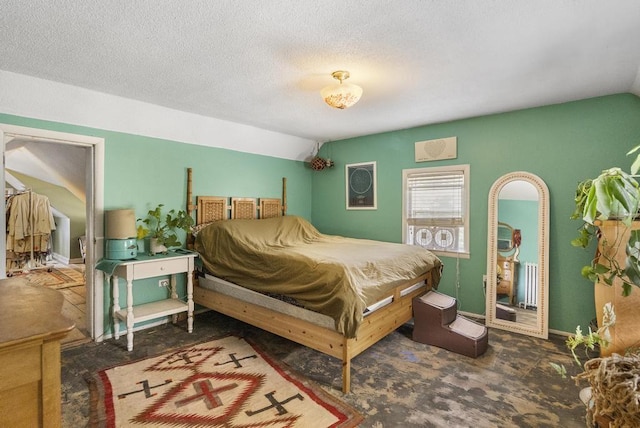 bedroom featuring vaulted ceiling and a textured ceiling