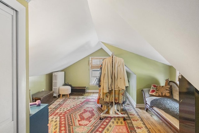 additional living space featuring vaulted ceiling, radiator, and hardwood / wood-style floors