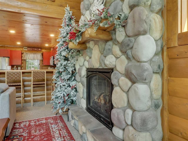 living room with wood ceiling, a stone fireplace, and carpet