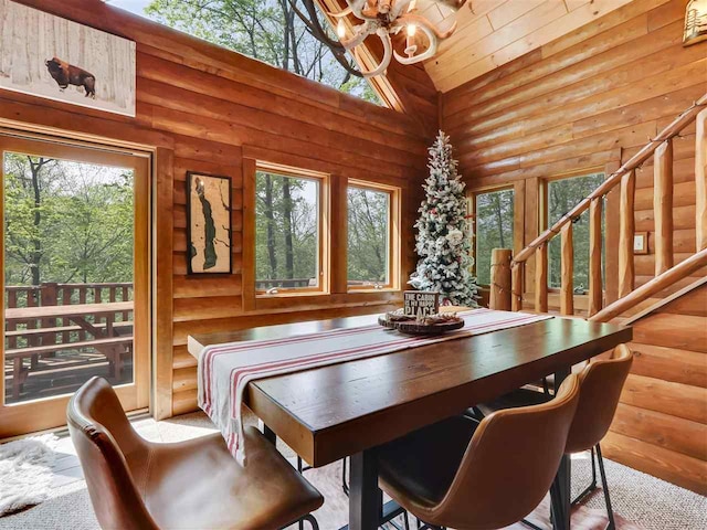 dining room with a healthy amount of sunlight, log walls, high vaulted ceiling, and a notable chandelier