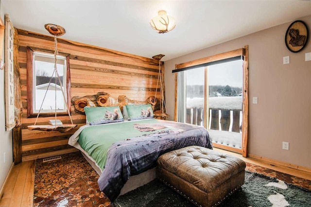 bedroom with hardwood / wood-style floors and wood walls