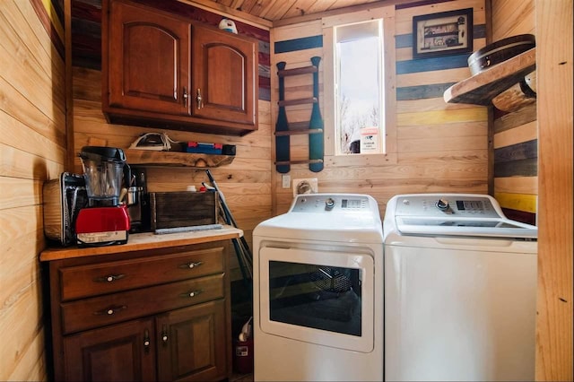 washroom featuring cabinets, washer and clothes dryer, and wood walls