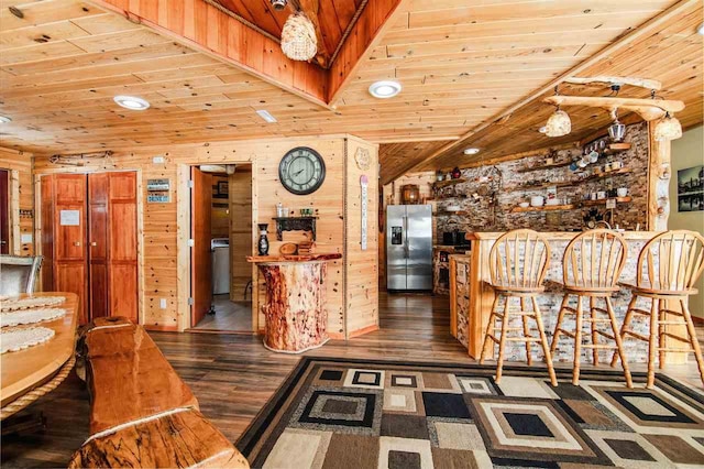 interior space with stainless steel refrigerator with ice dispenser, wooden walls, dark wood-type flooring, and wooden ceiling