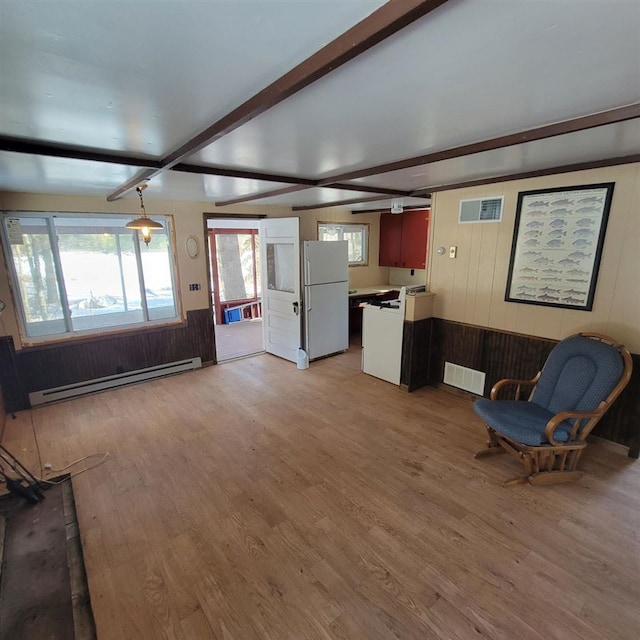 unfurnished living room with beamed ceiling, a baseboard radiator, wood-type flooring, and wooden walls